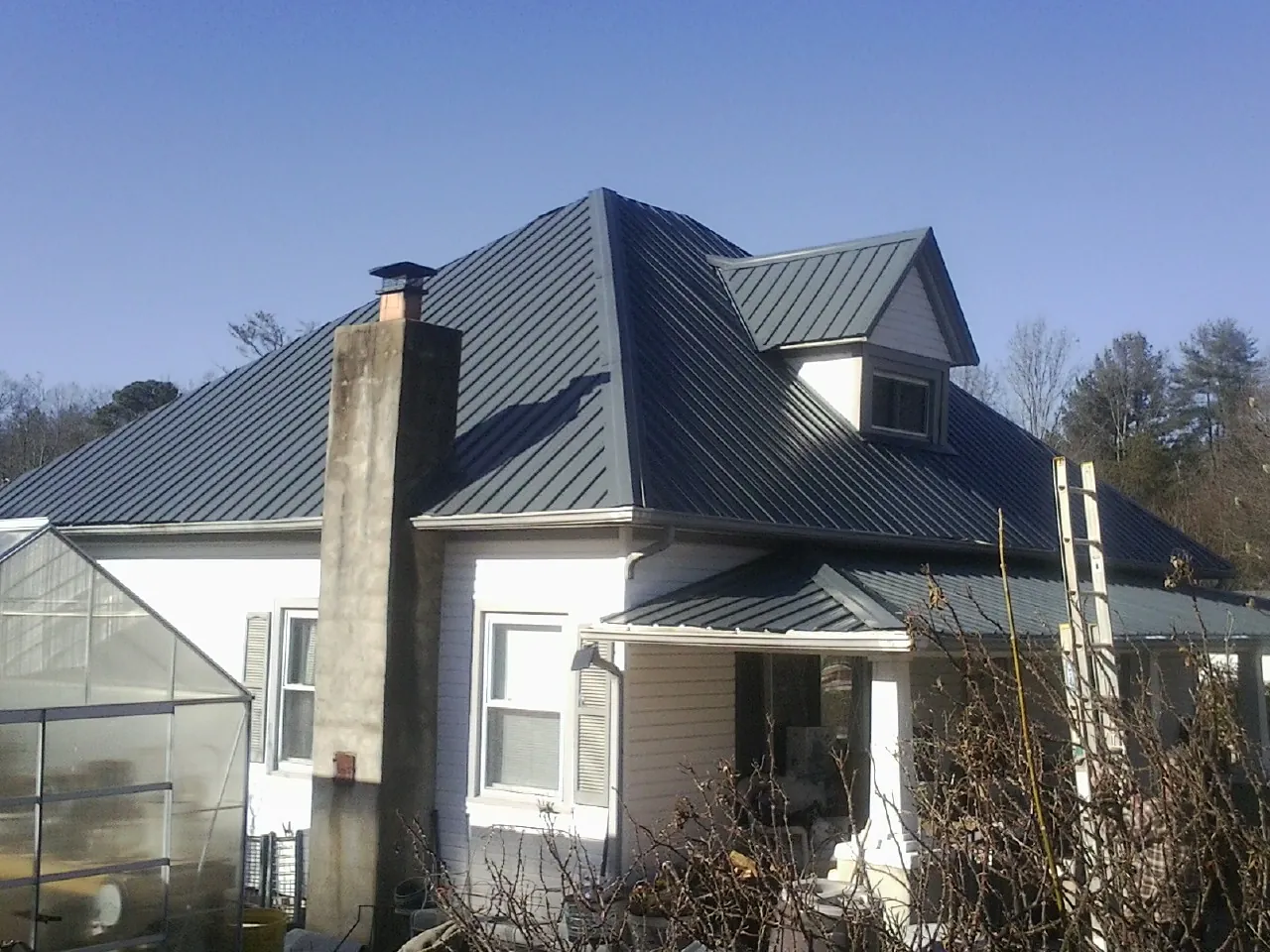 Dark blue standing seam metal roof on a white farmhouse with dormer — Slate & Tile Roof Repair by Roofing Brothers in Roachdale