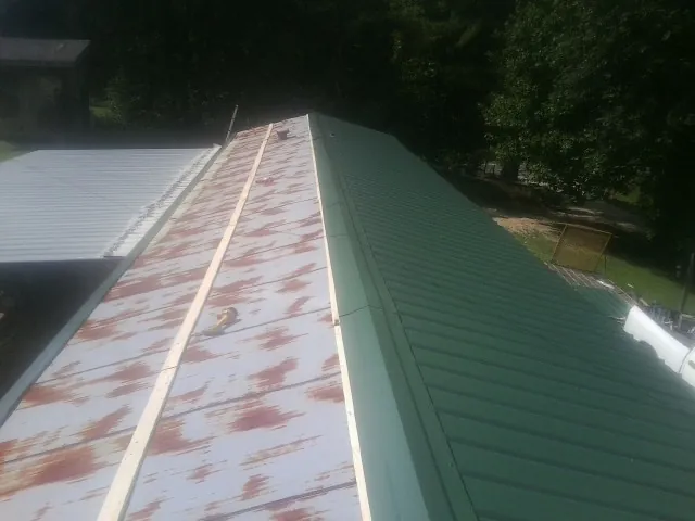 Old rusted panels beside newly installed green metal roofing — Wind Damage Roof Repair by Roofing Brothers in Roachdale