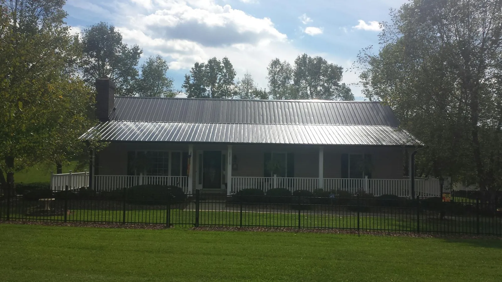 Gray metal roof on a brick ranch with a full width front porch — Gutter Guard Installation work by our crew in Roachdale
